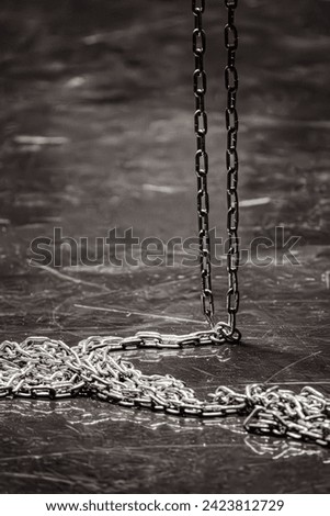 Iron chain on a dark background. Chain links. Solid rope. Steel structure. Sequential connection of rings. Long cargo chain. Accessory for sadomasochism. Black and white. 