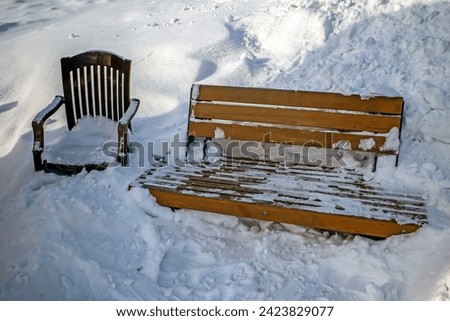 Snow-covered furniture in a park alley on a winter day