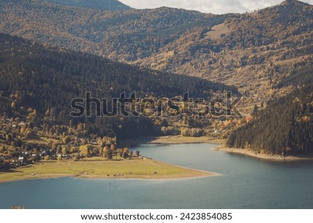 view of the village standing on the shore of Lacul Bicaz, Romania. beautiful lake in forest in mountains. An aerial shot of a magical town in the evening light in autumn. 