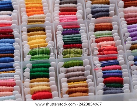 Plastic sorting box full of bobbins with different colour embroidery threads. Royalty-Free Stock Photo #2423854967