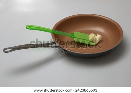 picture of butter on spatula in frying pan.