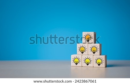 Brainstorming creative ideas and innovation concept. Pyramid stacked wooden cube blocks with dimming to bright light bulb icon. Creative process thinking to solve problems and start up ideas.