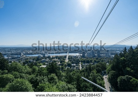 A photo of the Portland Aerial Tram with the Portland Skyline and Mt. Hood in the background on a clear sunny summer day as viewed from the Oregon Health and Science University.