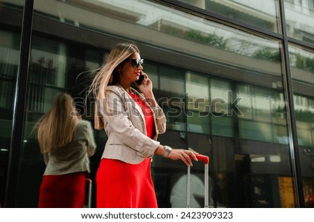 Young woman with suitcase and sunglasses talking on the phone, closeup shot 