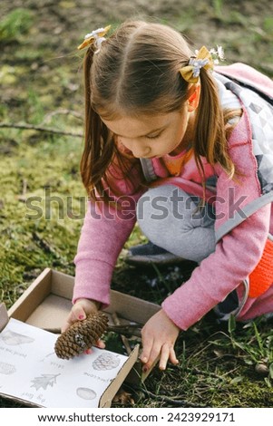 Scavenger hunt for kid in the park. Girl learning about environment. Natural education activity for World Earth day. Exploring in spring. Royalty-Free Stock Photo #2423929171