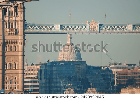 Scenic London view featuring the Tower Bridge's Victorian Gothic architecture and St. Paul's Cathedral's iconic dome, bathed in warm light, with ongoing city development.