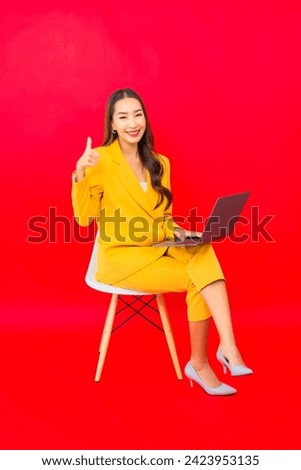 Portrait beautiful young business asian woman use computer laptop on red background