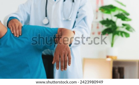 A physical therapist is treating a man with shoulder pain and suffering from frozen shoulder,pain and stiffness,unable to move,difficulty lifting his arm,male people with calcific tendonitis. Royalty-Free Stock Photo #2423980949