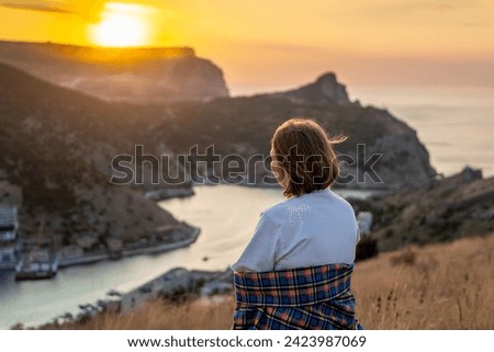 Happy woman on sunset in mountains. Woman siting with her back on the sunset in nature in summer. Silhouette.