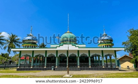 White mosque with three green-patterned domes