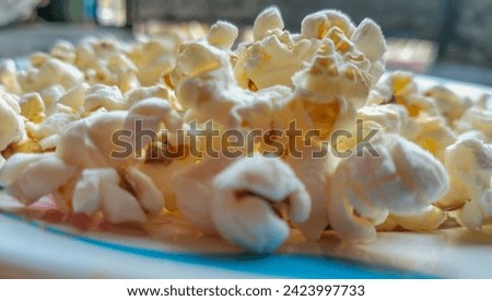 View of the classic plain salted butter popcorn. It is a variety of corn kernel which expands and puffs up when heated. Scattered salted popcorn, texture background. Film and cinema concept.