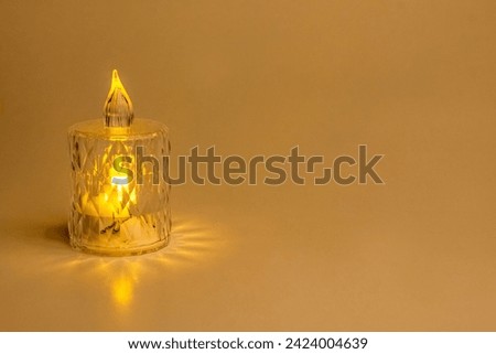 Burning battery-operated candle in a glass on white background, space for text. Royalty-Free Stock Photo #2424004639