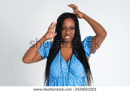 Shocked plus size model with wide open mouth on gray studio background, young African fat woman with curvy figure and pigtailed hairstyle