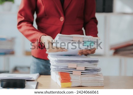 Woman's hands working in stacks of paper files to find and check unfinished documents, success in document folders at busy office Business document concept