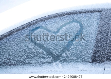 A heart painted on a car window made of snow. The snow heart.
