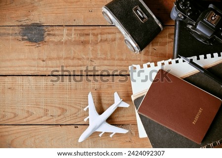 Travel concept with passport, camera, notebook and airplane on wooden background