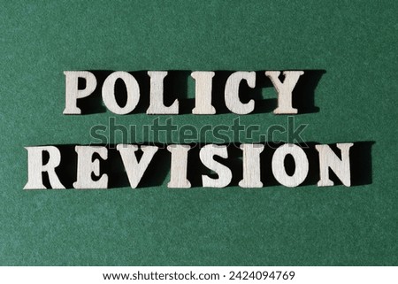 Policy Revision, words in wooden alphabet letters isolated on green background as banner headline