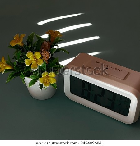 exquisite clock adorned with vibrant yellow flowers, elegantly placed next to a charming vase. This stunning timepiece effortlessly combines functionality with aesthetic appeal. Royalty-Free Stock Photo #2424096841