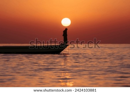 A fishing boat at sunrise off the coast of Fujairah, United Arab Emirates. Royalty-Free Stock Photo #2424103881