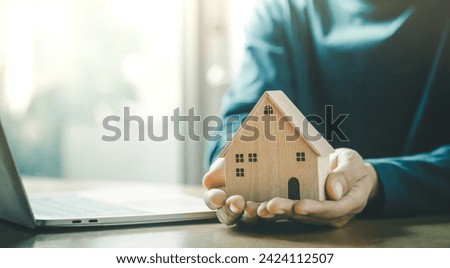 Choosing mini wood house model from model and row of coin money on wood table, selective focus, Planning to buy property.