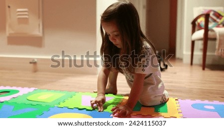 Little girl child playing with pieces of puzzles at home
