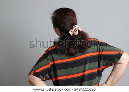 The 70s Chinese senior woman with casual clothes standing on the grey background. Royalty-Free Stock Photo #2424115625
