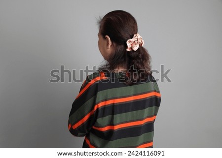 The 70s Chinese senior woman with casual clothes standing on the grey background. Royalty-Free Stock Photo #2424116091