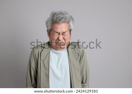 The 40s Asian man with smart casual clothes standing on the grey background.  Royalty-Free Stock Photo #2424129181