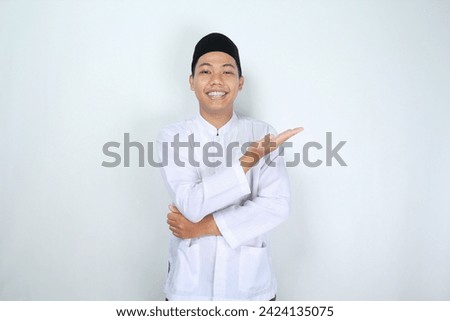 attractive muslim asian man presenting hand to the left side with smiling face isolated on white background, looking at camera