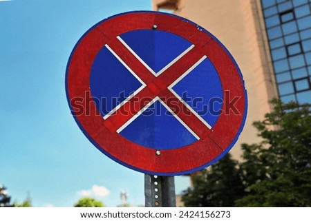 City Traffic and Safety Concept with a No Stopping or Parking Sign and a Modern Building, No Stopping or Parking Sign - Clear Blue Sky and Urban Background
