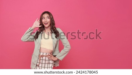 Young happy asian teen woman hand over ear listening an hearing to rumor or gossip and looking something away to side with smile on face isolated on pink copy space background. Royalty-Free Stock Photo #2424178045