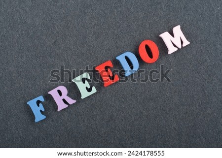 FREEDOM word on black board background composed from colorful abc alphabet block wooden letters, copy space for ad text. Learning english concept