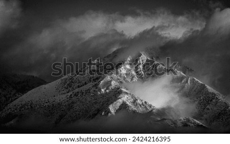Black and white image of Mountains in Angeles National Forest covered in snow during a storm. The shot is looking west from the 15 freeway at the Limonite Ave park and ride in Mira Loma Ca 