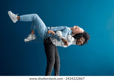 Playful young woman carrying her best friend on her back in a studio. Two vibrant young women having fun against a studio background.