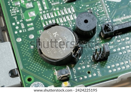 Detailed close-up view of a CMOS battery installed on a computer motherboard, BIOS memory power. Changing, replacing the cell abstract concept, nobody, object extreme closeup shot, technology Royalty-Free Stock Photo #2424225195