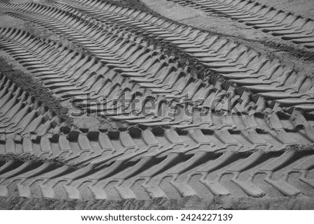 Sand tyre mark background. Tire track shape. Trail lines on dry brown sand pattern. Road construction site backdrop. Heavy machinery imprint. Dried mud vehicle wheel shape. Royalty-Free Stock Photo #2424227139