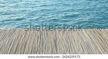 empty wooden building with bamboo roof made from stems on blue water texture background. Black sea coast. 