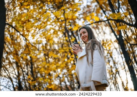 Young woman drinking coffee in the autumn forest