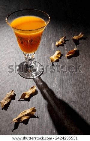 A glass of drink with hard light shining on it, showing the shadow of the glass extending over the table in an attractive way  Royalty-Free Stock Photo #2424235531