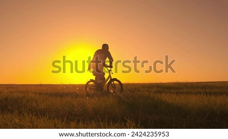 Little girl learns to ride bike with her dad in park in summer. Dad helps his daughter ride bike. Happy family. Father teaching daughter to ride bike. Child rides bike. Child, dad play together, sun