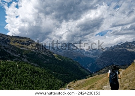 solo female hiker traverses a dirt path on the 5-lake journey, with the iconic Matterhorn veiled in dense clouds.