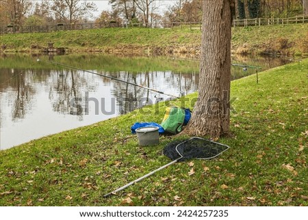 Three fishing rods and the fishermans' equipment by the side of a lake
