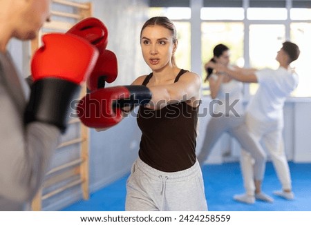 Sportive young girl training boxing in pair with her partner during sports classes