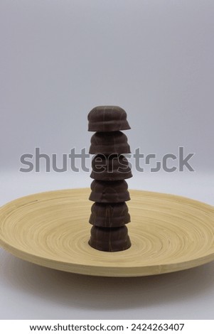 Stacked dark chocolate pralines on light wooden plate