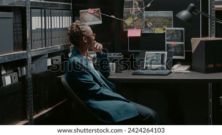 Private detective studying crime case information on board in archive room, examining files and forensic evidence. Law agent searching for suspect to solve felony, uncover details. Handheld shot. Royalty-Free Stock Photo #2424264103