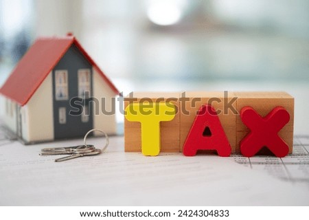 estate tax and inheritance tax concept. Tax word on wood block with house and property transfer documents.