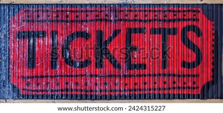 A very aged ticket box sign with black lettering on a red metal background.