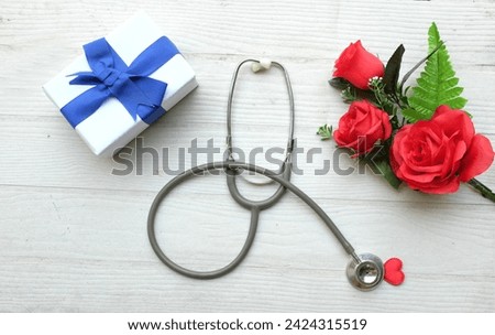Top view and copy space gift box, bouquet of red roses, stethoscope Red hearts, isolate on a wooden table white backdrop, Valentines Day concept. World Health Day, Doctors Day, Nurses Day