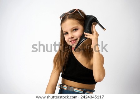Cute girl using a shoe like a telephone holding it in her face and talking, white background. Shopping sale, promotion, fashion and people concept.