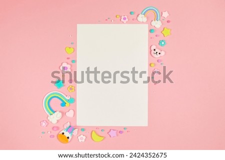 Blank white card on pastel pink background with frame of cute kawaii air plasticine handmade cartoon animals, stars, rainbows. Empty photo frames, baby's photo book, scrapbooking design template